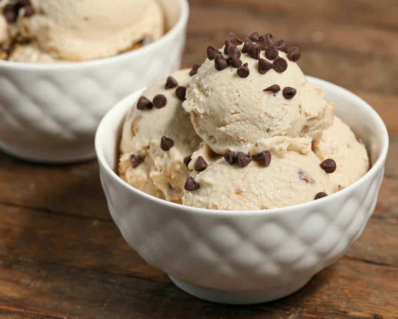 Two bowls of creamy peanut butter protein ice cream topped with chocolate chips